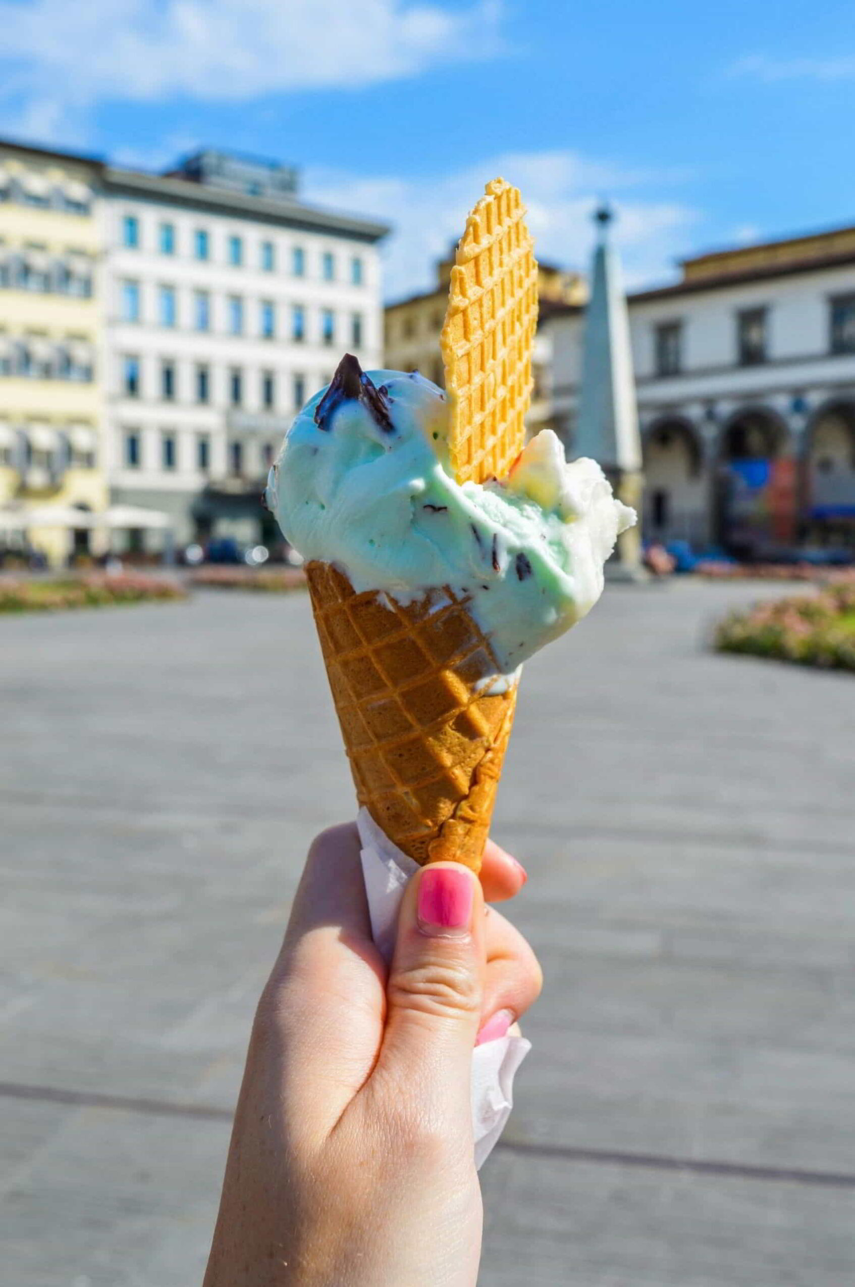 Hand holding gelato in the streets of Italy; read these Italy travel tips before visiting Italy