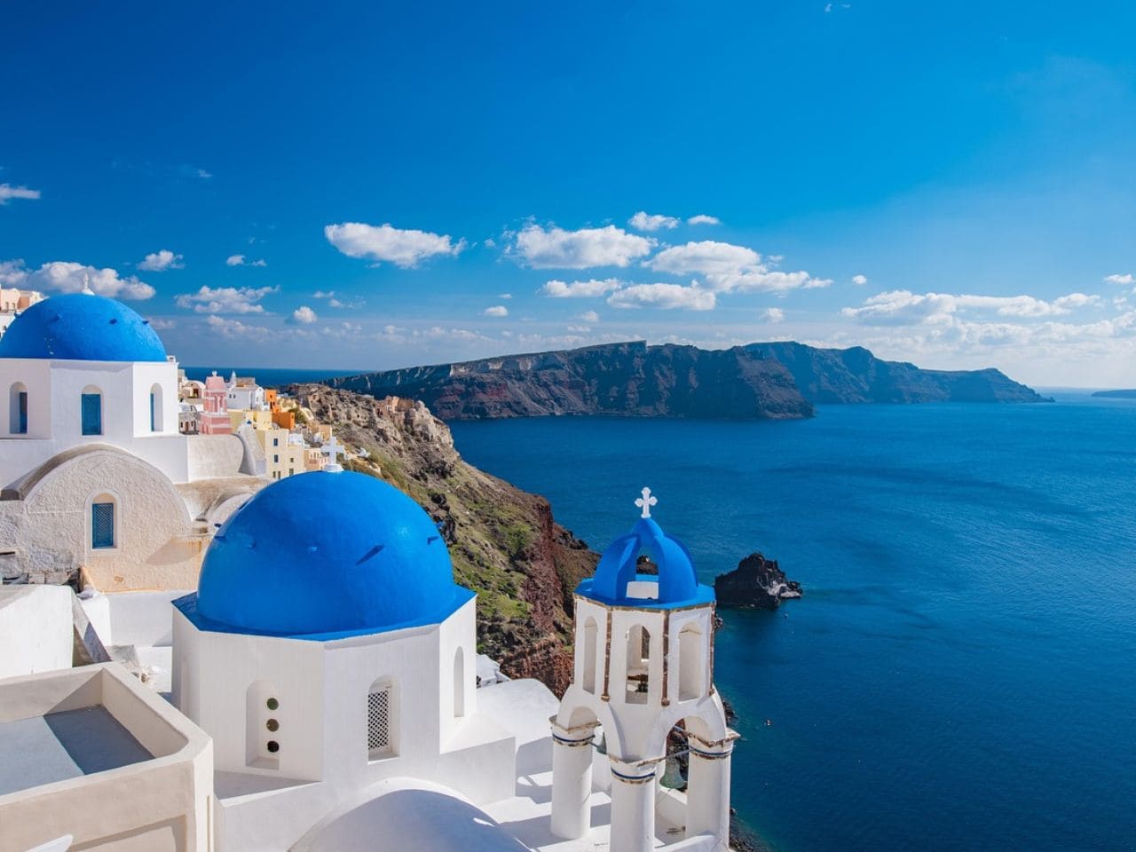 Cistinctive white-washed buildings with blue-domed roofs, particularly in villages like Oia and Fira in Santorini Greece