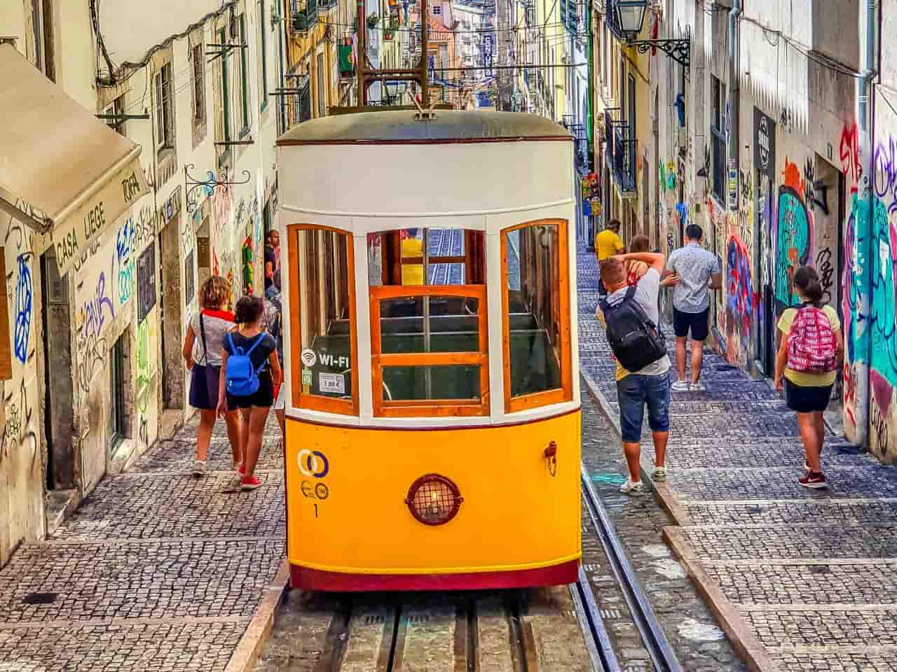 the iconic vintage yellow trams in Lisbon, Portugal, likely operating on the famous Tram 28 route.