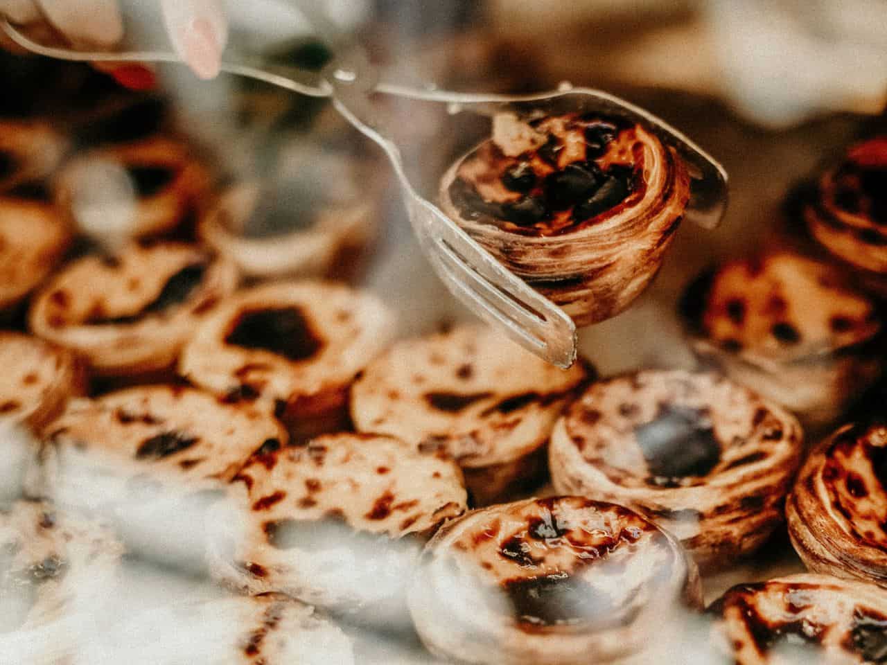 The image shows a display of Portuguese custard tarts, known as pastel de nata