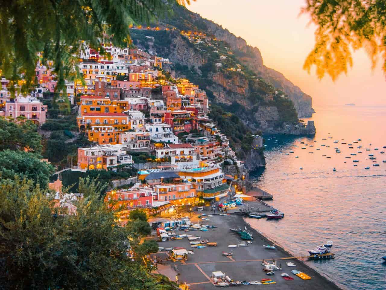 Sunset over Positano on the Amalfi Coast with cliffside buildings glowing in golden evening light