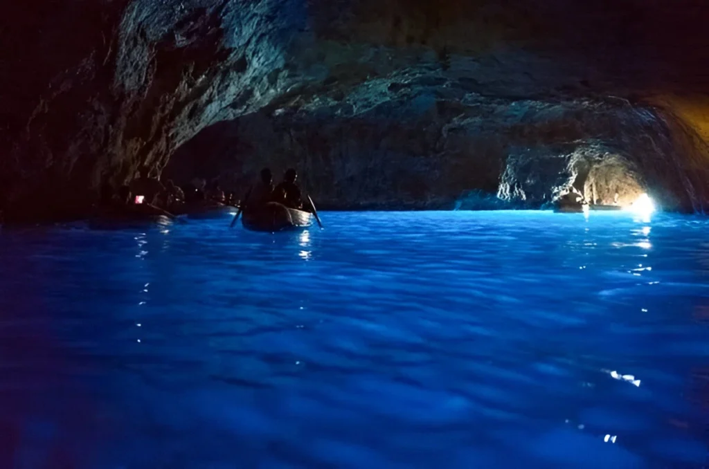 Visitors on boat exploring Blue Grotto during Capri travel trip