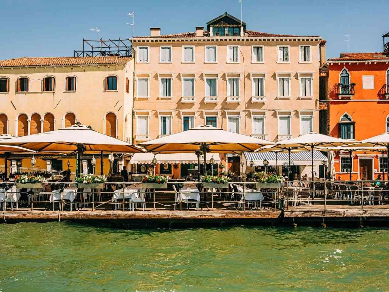 Picturesque cafe with parasols along a Venetian canal Italy