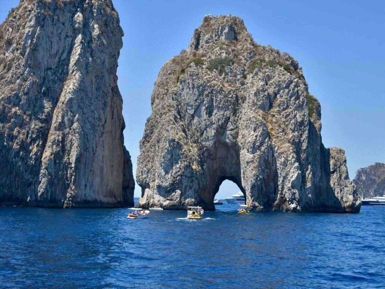 group of people in kayaks in front of Faraglioni rocks in Capri Italy